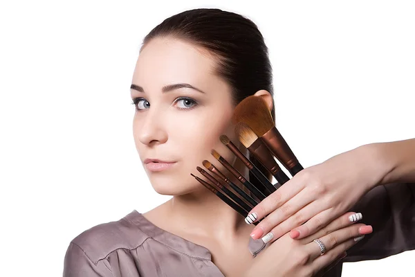 Hermosa joven sosteniendo diferentes pinceles de maquillaje. Aislado sobre un fondo blanco —  Fotos de Stock