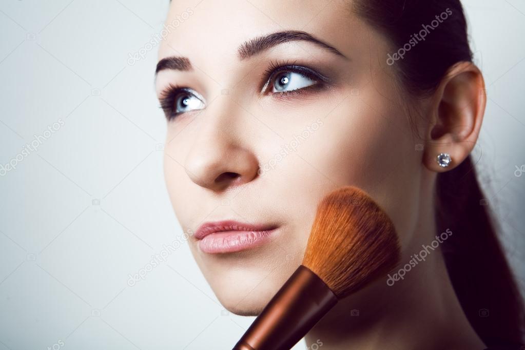 Beauty young Girl with Makeup Brushes. Natural Make-up for Brunette Woman with bleu Eyes. Beautiful Face. Makeover. Perfect Skin. Applying Makeup 