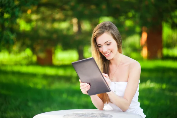 Pratty Frau im Park behält ihr Tablet — Stockfoto