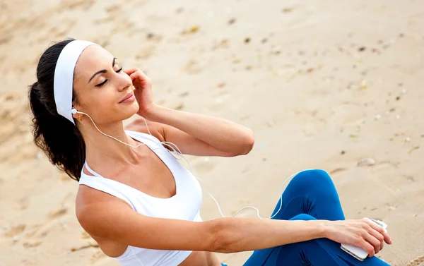 Jonge vrouw op het strand luisteren naar muziek — Stockfoto
