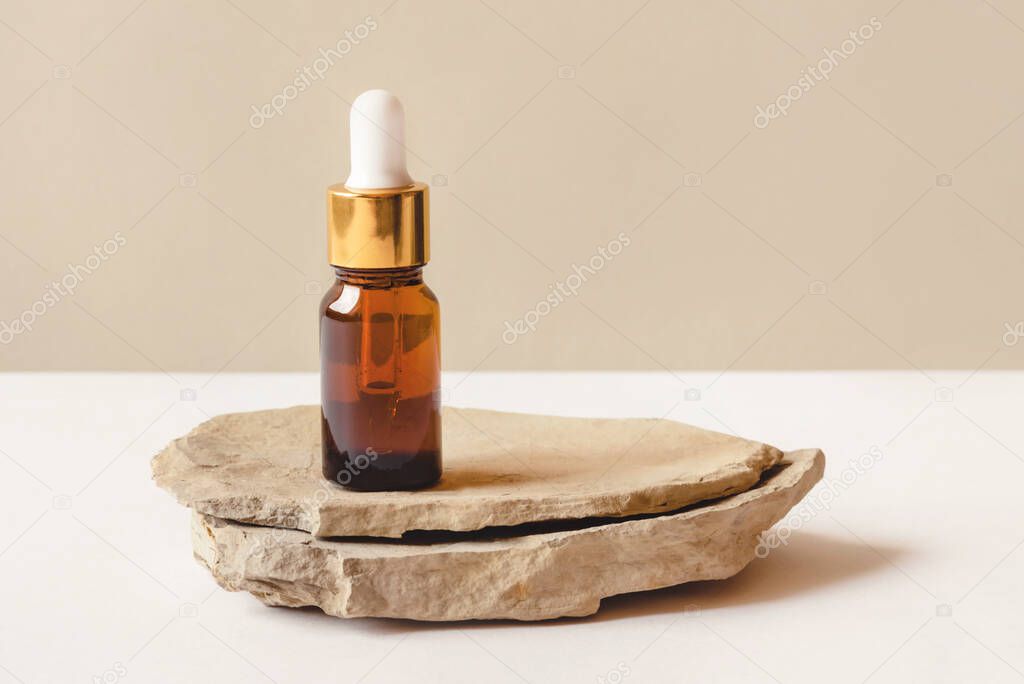 One brown bottle of cosmetics on a natural beige background.