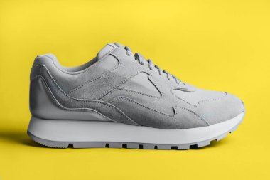 Sarı arka planda gri spor ayakkabı.