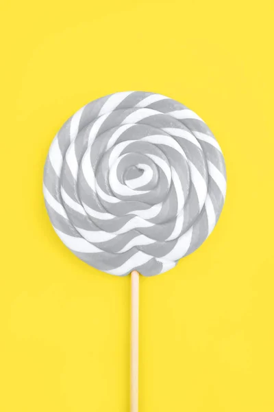 Gray lollipop in the shape of a circle on a yellow background. — Stockfoto