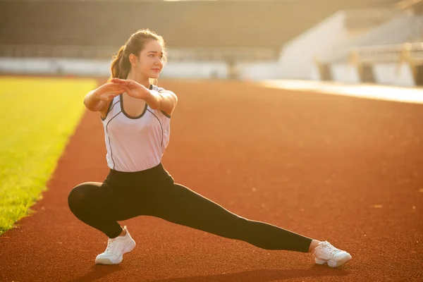 Chica de fitness haciendo ejercicio en la pierna en el estadio al aire libre — Foto de Stock