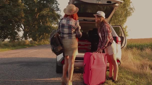 Девушки положить большой багаж в багажник автомобиля — стоковое видео