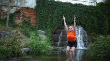 Yojik meditasyon uygulaması Yoga yapıyor. Şelaleye karşı suda yoga yapıyor.