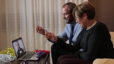 Üst düzey bir çift evdeki bilgisayardan oğullarını selamlıyor. Yılbaşı ve yeni yıl kavramına sosyal uzaklık