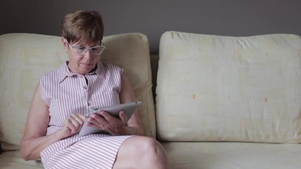 Vista lateral cercana de la mujer mayor jubilada usando tableta digital — Vídeos de Stock
