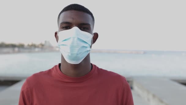 Retrato de un joven negro feliz quitando la máscara protectora al aire libre — Vídeos de Stock