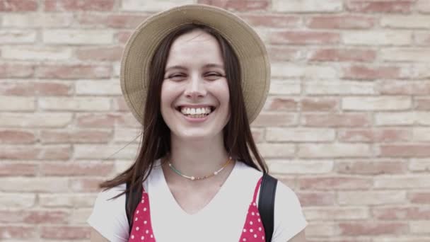 Портрет молодой счастливой туристки в шляпе, смотрящей в камеру — стоковое видео