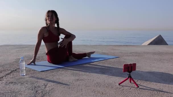 Fiatal sportos edzőnő jógázik a szabadban — Stock videók