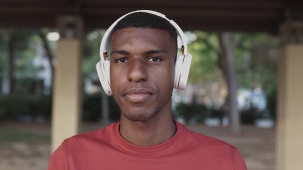 Porträtt av glad ung svart man med hörlurar tittar på kameran — Stockvideo