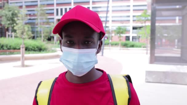 Entrega homem em uniforme vermelho decolando máscara protetora e sorrindo — Vídeo de Stock