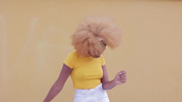 Mujer afro sonriente bailando mientras escucha música con auriculares inalámbricos — Vídeo de stock