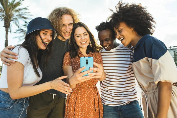 Багаторасова група молодих людей дивиться на смартфон на вулиці . — стокове фото