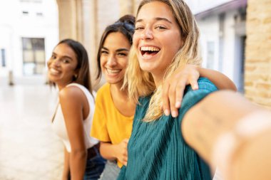 Şehir caddesinde telefonla selfie çeken üç neşeli çok ırklı bayan arkadaşın portresi - arkadaşlık ve milenyum insanları konsepti