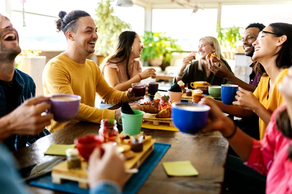 Sonriente grupo de amigos diversos desayunando y hablando en el bar de café — Foto de Stock