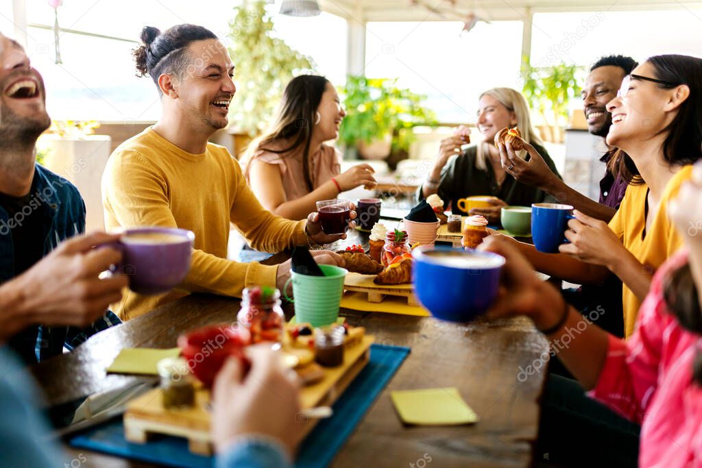 Smiling group of diverse friends having breakfast and talking at coffee bar