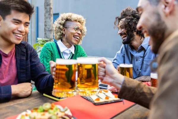 Jóvenes felices celebrando juntos mientras brindan por la cerveza y socializan — Foto de Stock