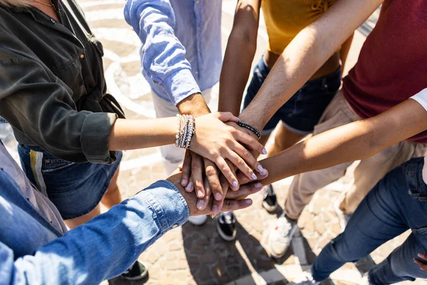 Group of young college students work team celebrating together outdoors - Community, teamwork, unity and friendship concept