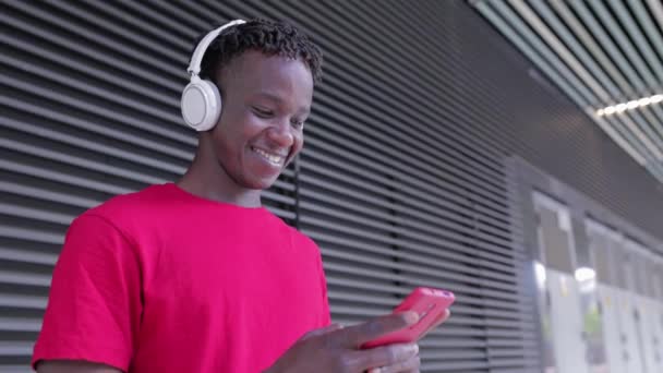 Glücklicher junger Afrikaner mit Handy auf der Straße — Stockvideo