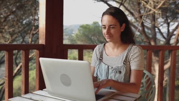 Jovem mulher trabalhando no laptop enquanto se senta no terraço em casa — Vídeo de Stock