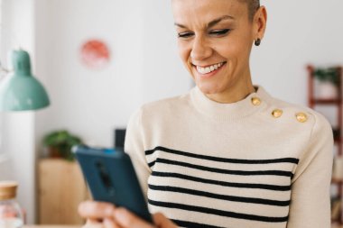 Ofiste dizüstü bilgisayarla çalışırken akıllı telefon kullanan yetişkin bir iş kadını. Teknoloji konsepti.