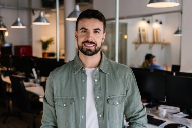 Ortak çalışma alanında duran, kameraya kendinden emin genç bir adamın portresi. İş ve Serbest Çalışanlar Konsepti