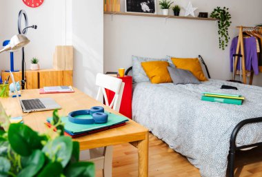 Yatağı, masası ve çalışma alanı olan parlak bir genç yatak odası. Mobilyaları, kitapları ve kişisel eşyaları olan rahat ve şık bir iç tasarım. Gençlik yaşam tarzı ve ev dekorasyonu konsepti.