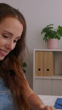 Öğrenci kadının internetteki öğrenimine odaklanmış dikey HD videosu. Evde sanal dersi takip ederken dizüstü bilgisayar kullanarak ve not alarak. Eğitim ve e-öğrenim yaşam tarzı kavramı.