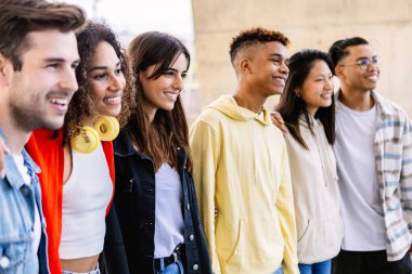 Bir grup neşeli çoklu etnik öğrenci bir arada duruyor, çeşitliliklerini kucaklıyor ve arkadaşlıklarının tadını çıkarıyorlar.