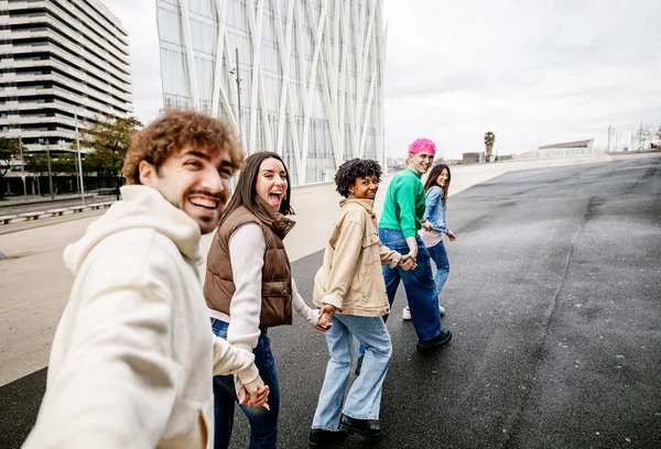 Şehirde el ele tutuşurken koşan bir grup genç öğrenci. Arkadaşlık kavramı
