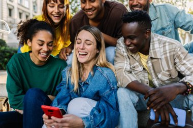 Çok ırklı gençler telefonda sosyal medyanın içeriğini izlerken eğleniyorlar. Teknoloji yaşam tarzı ve sosyal medya kavramı