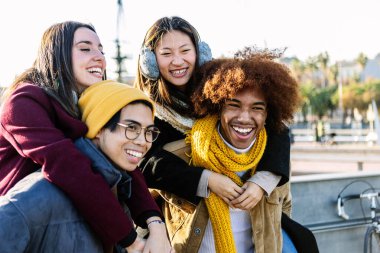 Neşeli, çoklu etnik kökenli bir grup genç, güneşli kış günlerinde sırtında gezintiye çıkıyor.