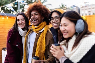 Mutlu çeşitli arkadaş grupları Noel pazarında sıcak içeceklerin tadını çıkarıyor. Kış tatili kavramı