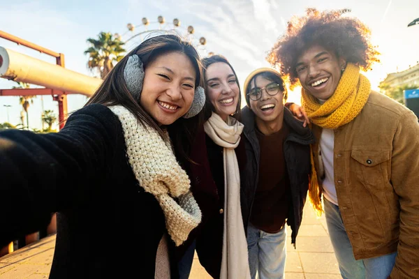 Genç ve mutlu arkadaşlar kışın şehir caddesinde selfie çekerken eğleniyorlar. Arkadaşlık kavramı
