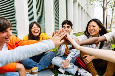 Üniversite kampüsünde el ele tutuşan bir grup öğrenci. Destek ve gençlik toplumu kavramı