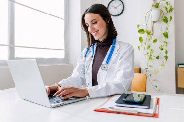 Hastanede dizüstü bilgisayarda çalışan genç ve güzel bir bayan doktor.