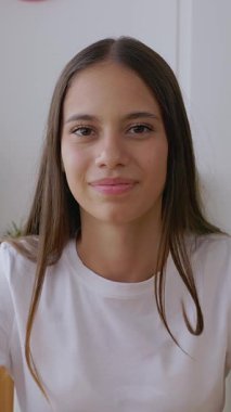 Dikey HD video. İnternetteki bir dersi takip ederken ya da bir arkadaşıyla sohbet ederken dikkatle dinleyen 15 yaşındaki bir kız öğrencinin görüntüsü.