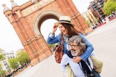 Barcelona 'daki Arc de Triomf' u gezerken mutlu kıdemli turistler. Mutlu, olgun bir çift, tatil sırasında eğlencenin tadını çıkarıyor. Seyahat ve yaşam tarzı kavramı.