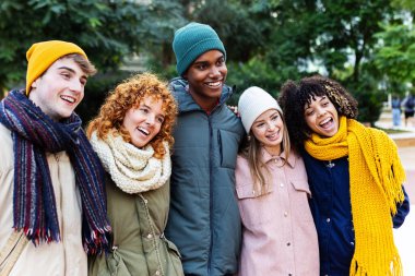 Kış kıyafetleri giymiş bir grup genç arkadaş şehir caddesinde birlikte eğleniyorlar. Gençlik toplumu ve arkadaşlık kavramı