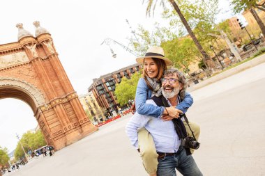 Oyuncu yaşlı çift Barcelona 'daki Arc de Triomf' ta tatilin tadını çıkarıyor. Gezintiler sırasında birlikte gülen neşeli olgun turistler. Seyahat ve yaşam tarzı kavramı.