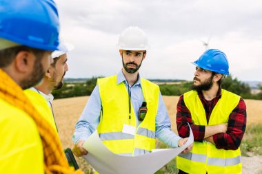 Bir rüzgar çiftliği inşaatının planlarını ve planlarını tartışan mühendislerden oluşan bir ekip sürdürülebilir kalkınma için işbirliği yapıyor. Yenilenebilir enerji ve endüstriyel işgücü kavramı