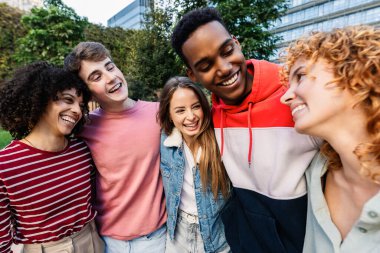 Şehir parkında gülen mutlu bir grup genç arkadaş. Farklı arkadaşlar, rahat bir açık hava anında neşeli bir sohbet ediyorlar. Arkadaşlık ve refah kavramı.