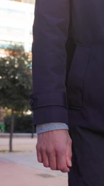 Modern bir şehir caddesinde yürürken şık bir trençkot ve kot pantolon giyen tanınmamış bir işadamı güneşli bir günde hafif bir esintiyle işe gidip geliyor. Dikey HD video