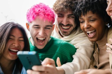 Üniversite öğrencilerinden oluşan çok kültürlü bir grup açık havada dinleniyor, telefondaki içerikleri inceliyorlar. Gençlik toplumu ve teknoloji yaşam tarzı kavramı.