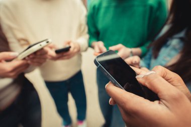 Young group of people using mobile phones, text message on cell app. Social media and technology lifestyle concept