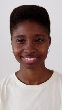 İş yerinde kameraya gülümseyen genç siyahi kadının dikey HD portresi