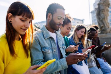 Dışarıda akıllı telefonlar kullanan bir grup genç öğrenci. Gençlik ve teknoloji yaşam tarzı konsepti