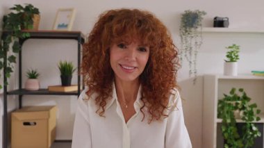 POV kamera görüntüsü ya da ofisteki mutlu çekici iş kadınının ön portresi. Orta yaşlı bir kadının ev ofisinden kameraya gülümseyen bir fotoğrafı..